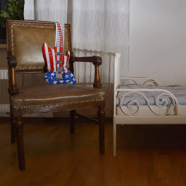 Guitarra de juguete inflable en un sillón vintage de cuero —  Fotos de Stock