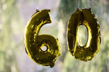 60 yaşındaki altın dekoratif figürler bir pencereye asılı.