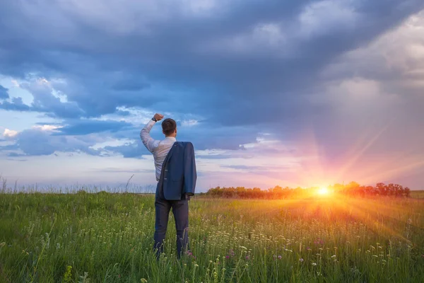 Geschäftsmann im eleganten Anzug mit Jacke über der Schulter im Feld stehend — Stockfoto