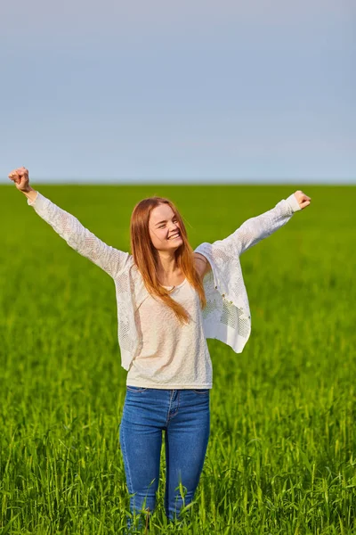 Girl with open arms on a green wheat field — Stock Photo, Image