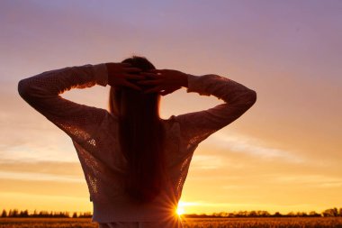 Sabah şafak arka plan üzerinde beyaz sundress kırmızı kıvırcık saçlı bir kadın