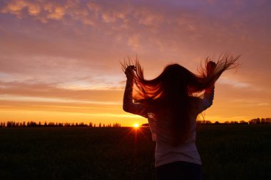 Sabah şafak arka plan üzerinde beyaz sundress kırmızı kıvırcık saçlı bir kadın