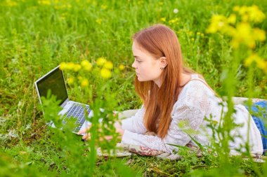 Çim üstünde laptop ile gülümseyen kız