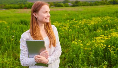 Çim üstünde laptop ile gülümseyen kız