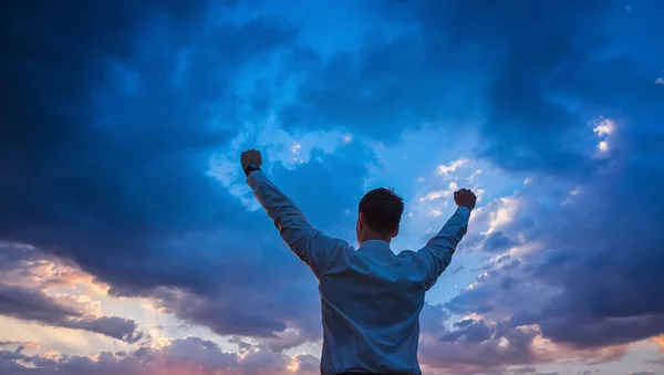 Щасливий бізнесмен, стоячи в полі над вітровим фоном з руками вгору і великими пальцями вгору — стокове фото