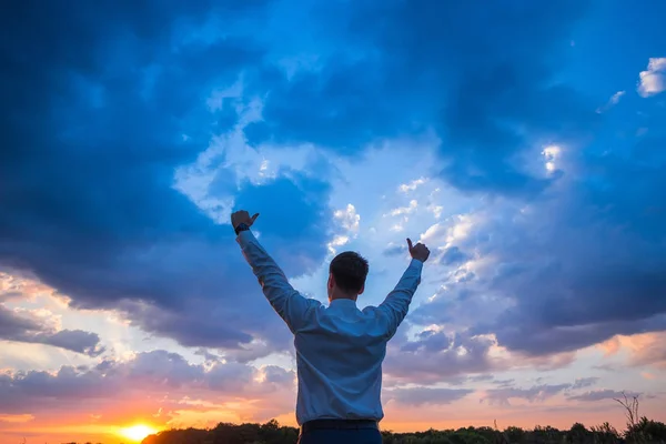 Hombre de negocios feliz, de pie en el campo sobre el fondo del viento con las manos arriba y pulgares hacia arriba —  Fotos de Stock