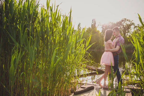 Göldeki aşıklar. Bu genç adam gün batımında gitar çalarken genç çift parkta, suyun kenarında oturuyor..