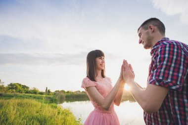 Göldeki aşıklar. Bu genç adam gün batımında gitar çalarken genç çift parkta, suyun kenarında oturuyor..