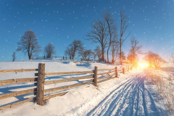 Vinter land landskap med virke staket och snowy road — Stockfoto