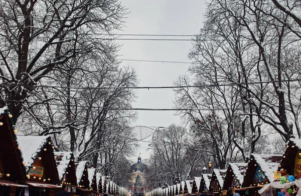 Hermoso centro de la ciudad y cabañas de madera para el mercado cubierto de nieve. plaza de la ciudad nevada en Lviv . — Foto de Stock