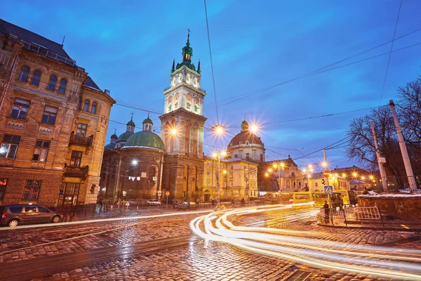 Vista panorámica del campanario iluminado de la iglesia de la Asunción al atardecer con tranvía vintage en primer plano, Lviv, Ucrania . —  Fotos de Stock