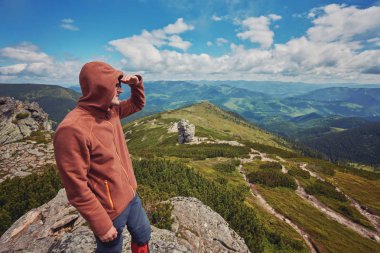 Üstünde tepe-in rock bulutlar arka planda duran adam.