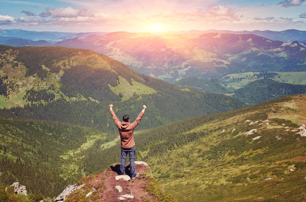 Glad turist står med ryggsäck på en bergstopp med rais — Stockfoto