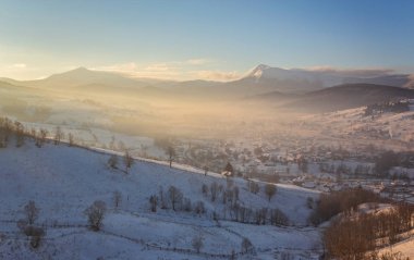 Kış masal, kar yağışı kaplı ağaçlar ve dağ köyü evleri.