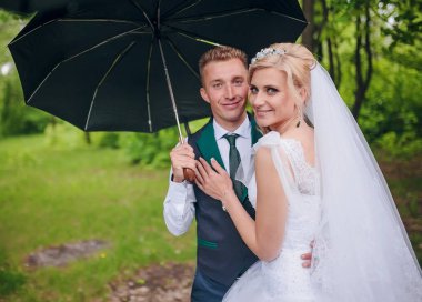 Güzel gelin ve damat Park şemsiyesi altında yürüyüş. Kızıl saçlı gelin.