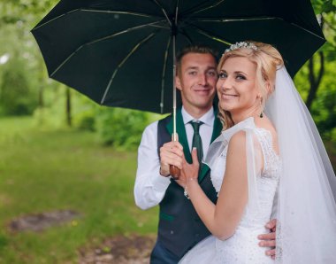 Güzel gelin ve damat Park şemsiyesi altında yürüyüş. Kızıl saçlı gelin.