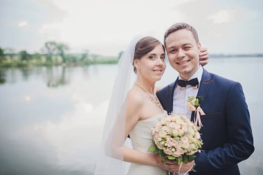 Şık gelin ve damat düğün günü dışarıda birlikte poz veriyorlar.