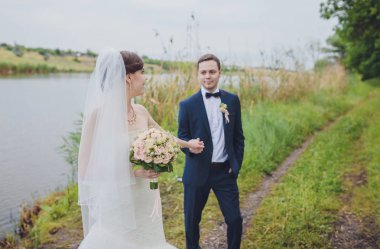 Şık gelin ve damat düğün günü dışarıda birlikte poz veriyorlar.