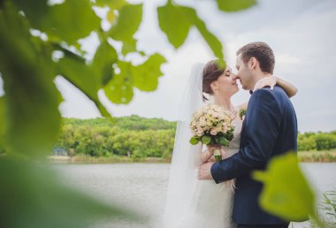 Şık gelin ve damat düğün günü dışarıda birlikte poz veriyorlar.