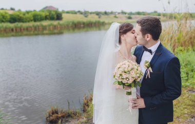 Şık gelin ve damat düğün günü dışarıda birlikte poz veriyorlar.