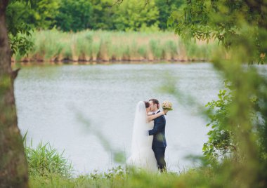 Şık gelin ve damat düğün günü dışarıda birlikte poz veriyorlar.