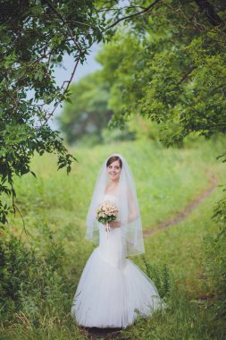 Şık gelin ve damat düğün günü dışarıda birlikte poz veriyorlar.