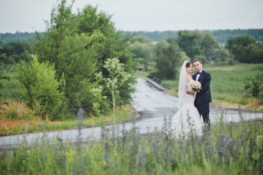 Şık gelin ve damat düğün günü dışarıda birlikte poz veriyorlar.