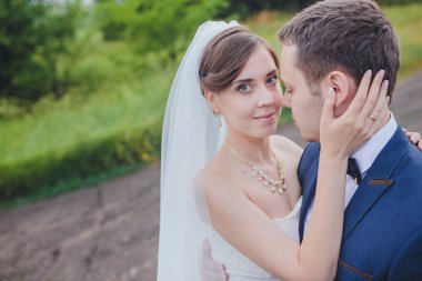 Şık gelin ve damat düğün günü dışarıda birlikte poz veriyorlar.