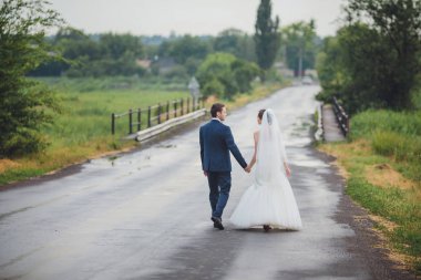 Şık gelin ve damat düğün günü dışarıda birlikte poz veriyorlar.