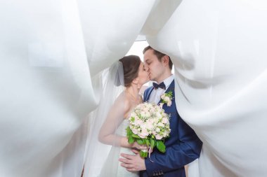 Şık gelin ve damat düğün günü dışarıda birlikte poz veriyorlar.