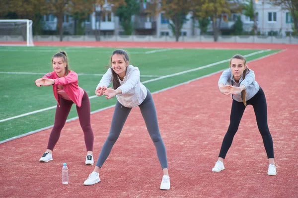 Pozitif kadın spor egzersizleri yapıyor... Üç güzel genç kadın spor güneşli bir günde parkta yapıyor grubu.