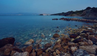 Taş ve kayalar ön planda kremsi sörf ve polis plajında akan, Kıbrıs.