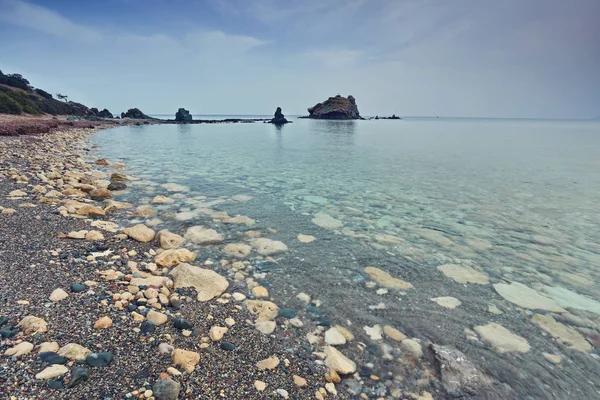 Piedras y rocas en primera línea con cremoso surf reflujo y fluir en la playa de Polis, Chipre . — Foto de Stock