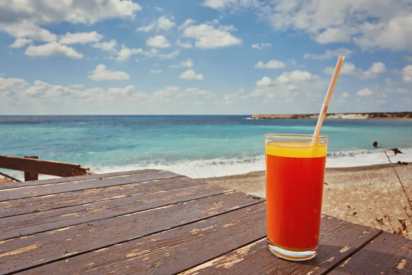 Melonensaft an einem Meeresstrand. Gläser mit rotem Getränk und Stroh stehen auf einer gefallenen Kokosnuss. — Stockfoto