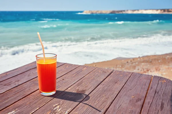 Melonensaft an einem Meeresstrand. Gläser mit rotem Getränk und Stroh stehen auf einer gefallenen Kokosnuss. — Stockfoto