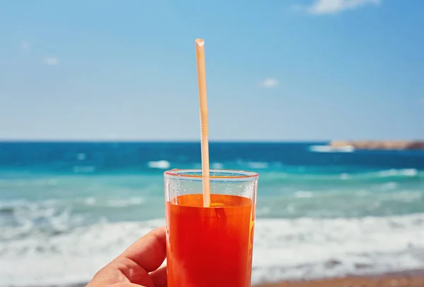 Frisches Getränk in der Hand des Mannes vor dem Hintergrund des exotischen Strandes — Stockfoto