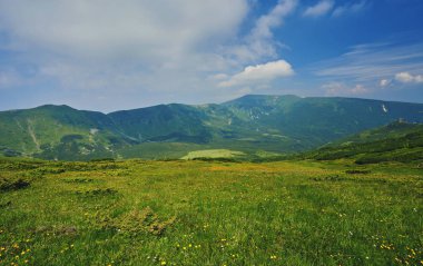 Dağlardaki yaz manzarası ve bulutlu koyu mavi gökyüzü.