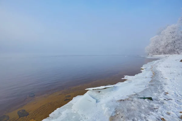 Ribera del río después de una nevada en un día nublado de invierno . —  Fotos de Stock