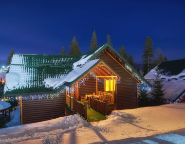 Hafif bir çelenkle süslenmiş bir kır evi. Kışın vahşi doğadaki kır evi..