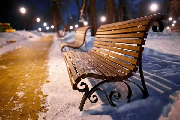 View of bench and shining lantern through snowing. — Stock Photo, Image
