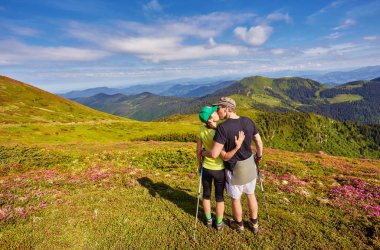 Erkek ve kadın dağın tepesinde ayakta ve sarılıyor, yaz yürüyüşü
