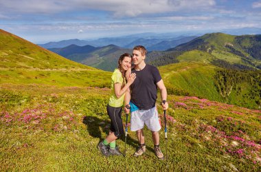 Erkek ve kadın dağın tepesinde ayakta ve sarılıyor, yaz yürüyüşü