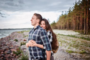 Göldeki aşıklar. Bu genç adam gün batımında gitar çalarken genç çift parkta, suyun kenarında oturuyor..