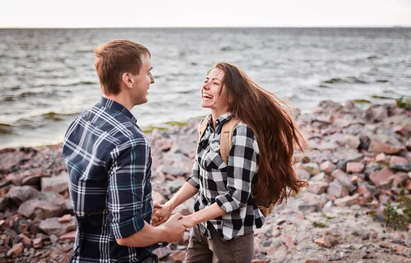 Amantes en un lago. Pareja joven enamorada sentada en el suelo del parque cerca del agua mientras estos jóvenes tocan la guitarra al atardecer. —  Fotos de Stock