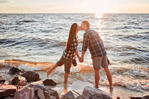 Liebespaar küsst sich bei Sonnenuntergang ins Wasser — Stockfoto