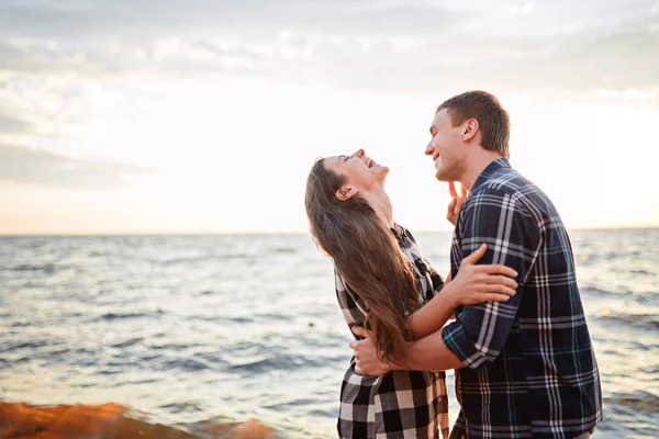 Amantes en un lago. Pareja joven enamorada sentada en el suelo del parque cerca del agua — Foto de Stock