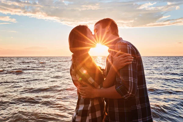 Pareja de amantes besándose en el agua al atardecer — Foto de Stock