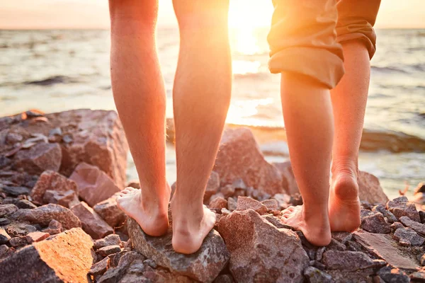 Legs on beach. Foot spa. A young loving couple hugging and kissing on the beach at sunset. — Stock Photo, Image