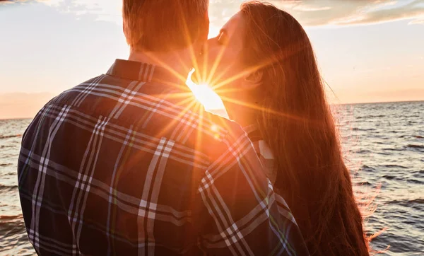 Pár szerelmeseinek csókolózás vízbe naplementekor — Stock Fotó