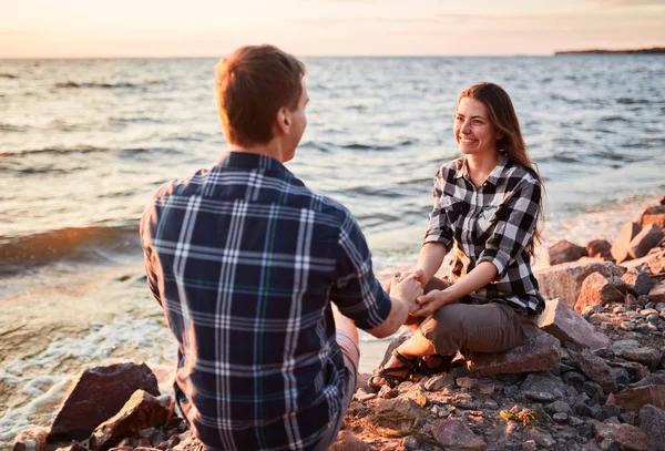 Amantes en un lago. Pareja joven enamorada sentada en el suelo del parque cerca del agua — Foto de Stock